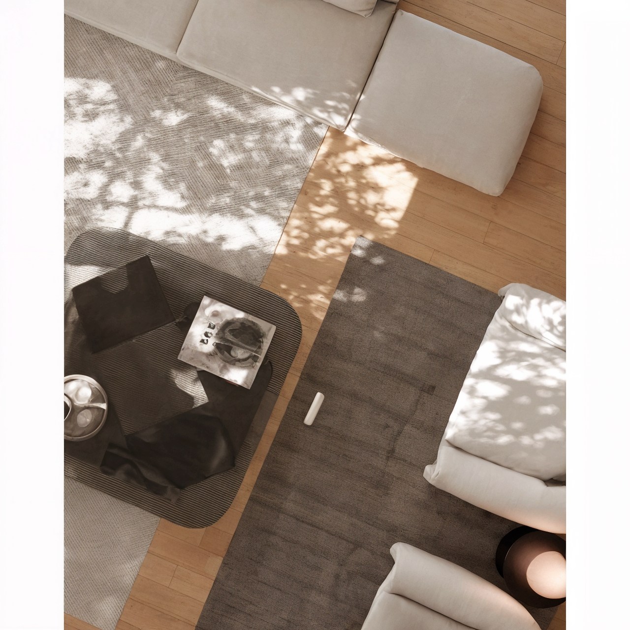 Overhead view of a curved white sofa, dark coffee table and layered neutral rugs.