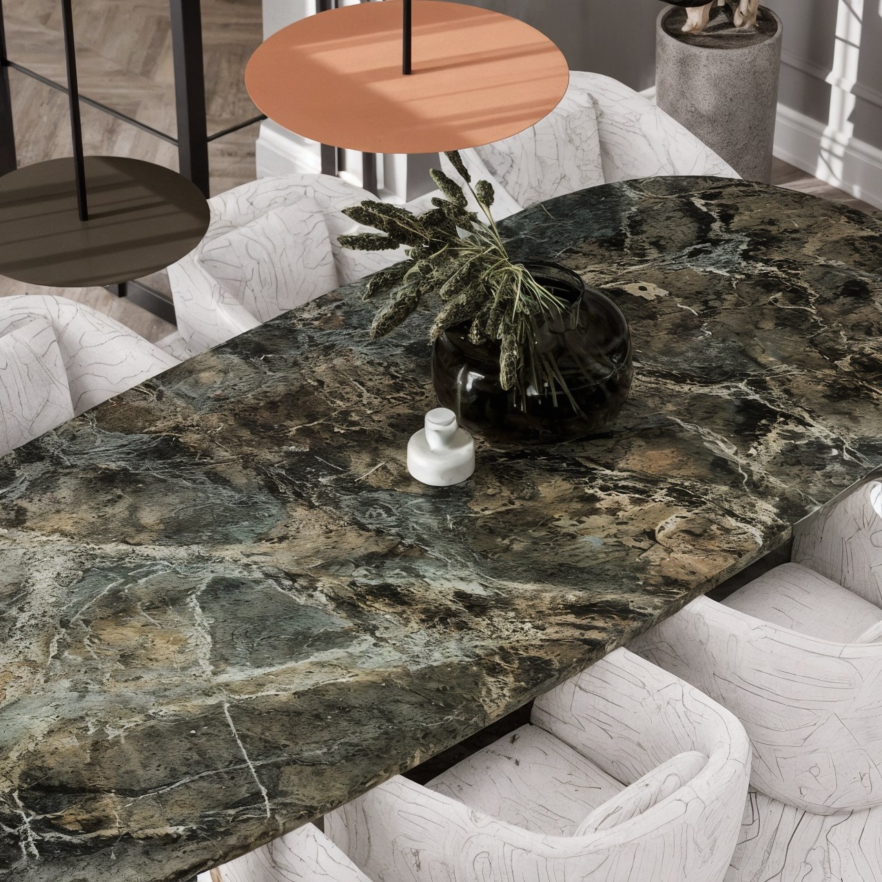 Dark green veined stone dining table with upholstered chairs and sculptural pendant lights.