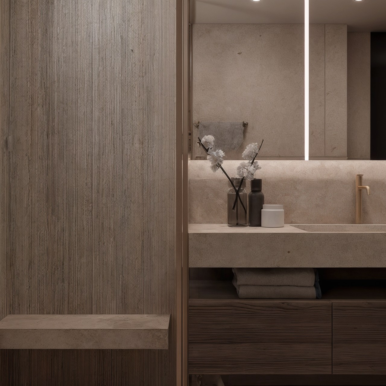 Stone basin and dark timber vanity beneath a large backlit mirror.